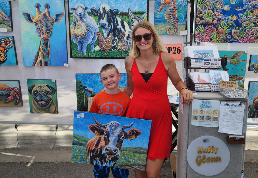 Holly Glenn and her son Thomas show some of the art in her booth.
