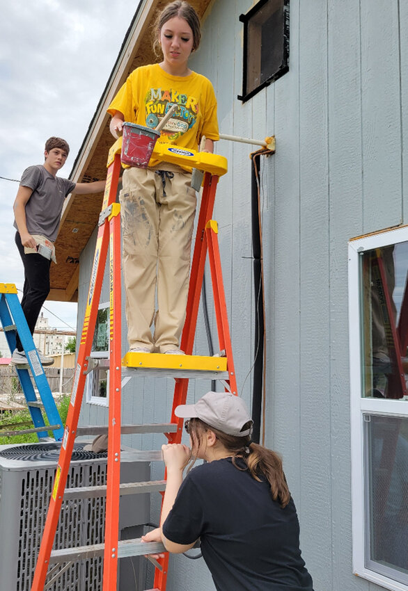 Will Reid, Kellie Lambertson and Sarah Tubbs paint new siding.