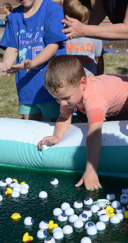 Four-year-old D. J. Duncan searches through Jello for floating balls in a less-muddy contest.