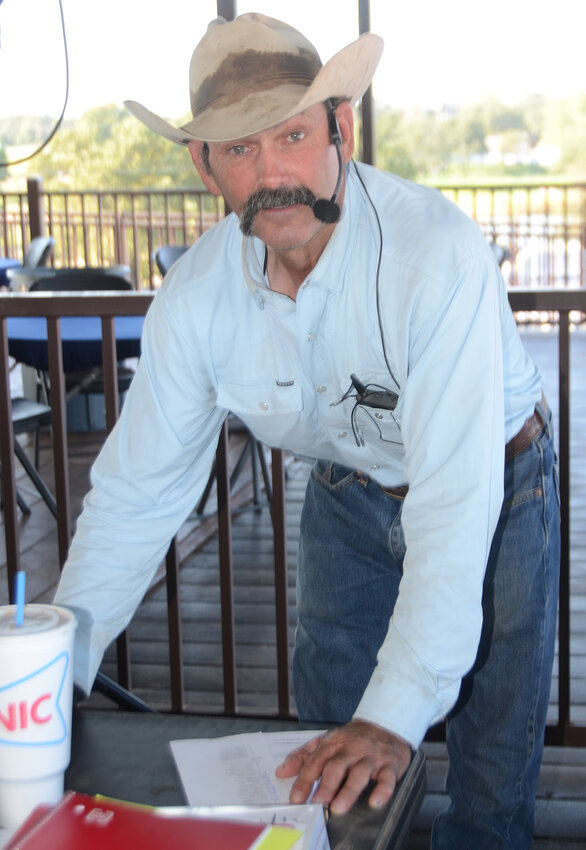 Bary Clower checks the list of registered contestants before emceeing the rodeo. The announcer has been entertaining at ranch rodeos for 21 years.