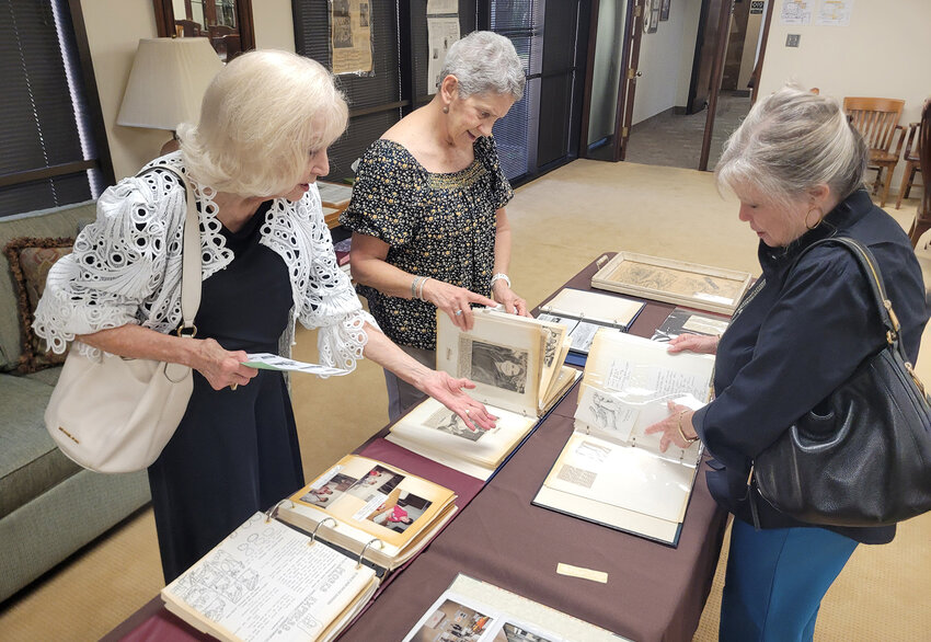 Myrlan Coleman, Susie Bossert, and Valerie Froehlich look through church scrapbooks. Froehlich found Coleman’s wedding announcement in the archives.