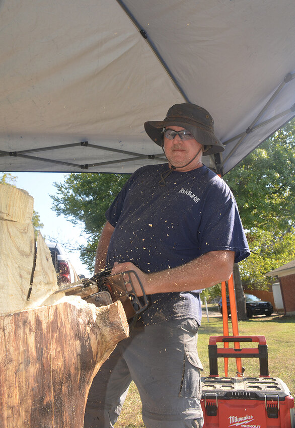 Ray Banfield carves an eagle on a pedestal with a chainsaw. The artist has a craft shot in Granbury.