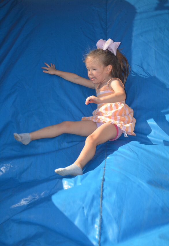 Three-year-old Isla Capps bounces her way down a slide.