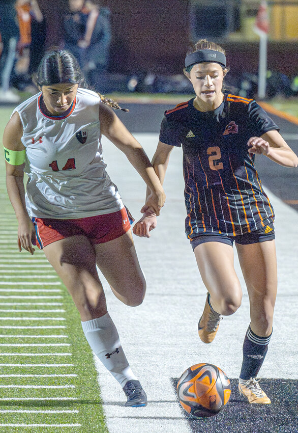 Emery Thompson races for the ball while being held by a Lady Texans player in 2024.