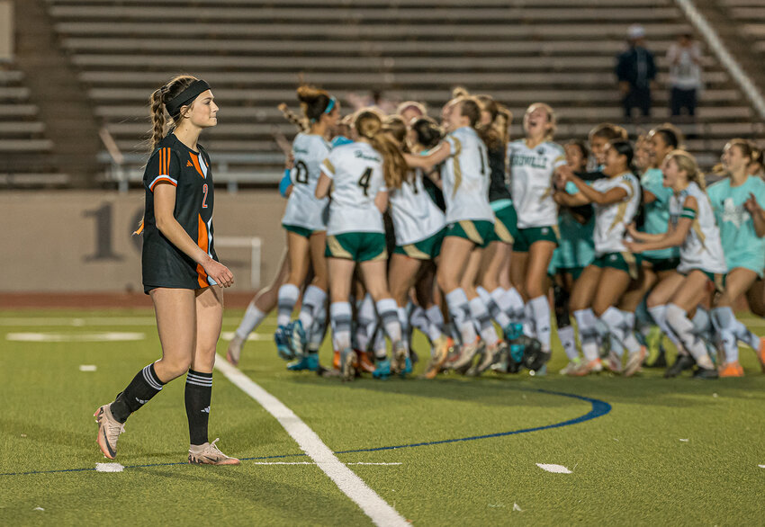 Dismayed, Emery Thompson walks off the pitch as Birdville celebrates in the background after edging out the Ladycats in a shootout, 3-2.
