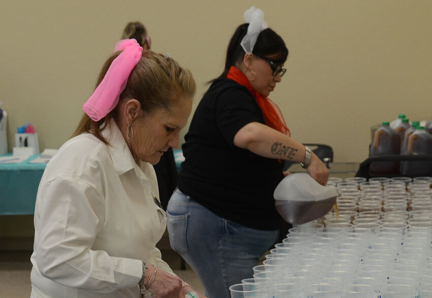 Volunteers Janie Hanna and Marie Ortez pour water and sweet peach tea for the banquet.
