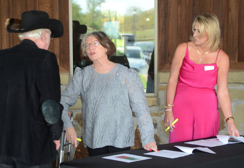 Peggy Hutton and Leslie Chalmers register Gayle Hicks at the banquet door. Hicks, a life-long artist, donated two works for the silent auction benefiting Meals on Wheels and the senior center.