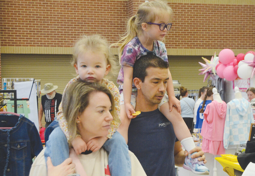 Three year-old Leighton and four year-old Waverly have the best seats in the house on top of parents Paige and Waylon Mugartefui as they shop clothes and crafts of Aledo Spring Fling.