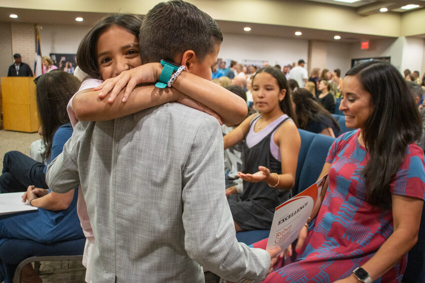 Bearcat of Character Ruben Cabral gets hugged by his family after being awarded a certificate from the board of trustees.