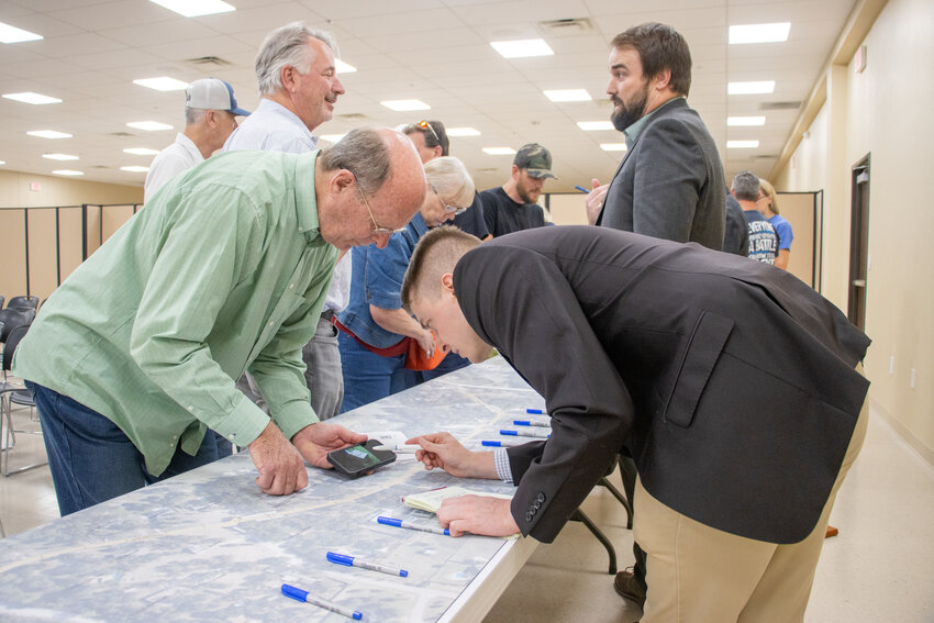 Squaw Creek resident Steve Ireson (left) shows Jacob Martin engineer Talmadge Fillingim (right) pictures of when the current water line flooded so severely it reached the Squaw Creek Golf Course.
