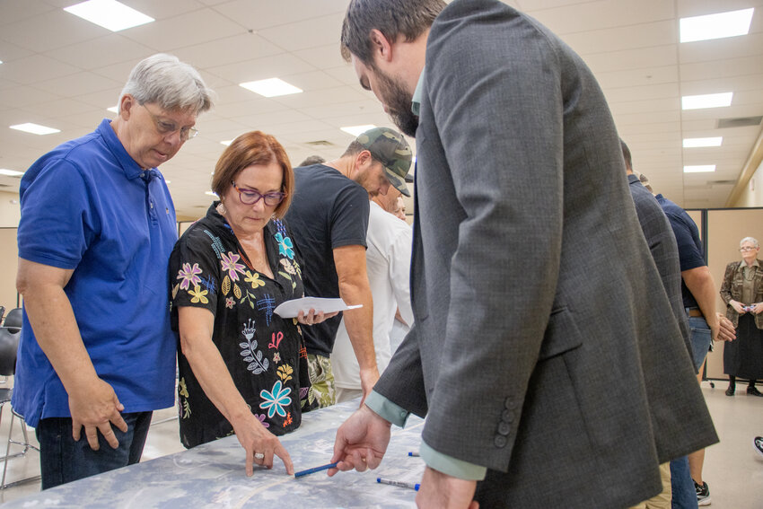 Squaw Creek residents Bruce and Barbara Willaims (left) speak with Jacob Martin engineer Nic Kirk (right) about where the new water line will be placed on their property.