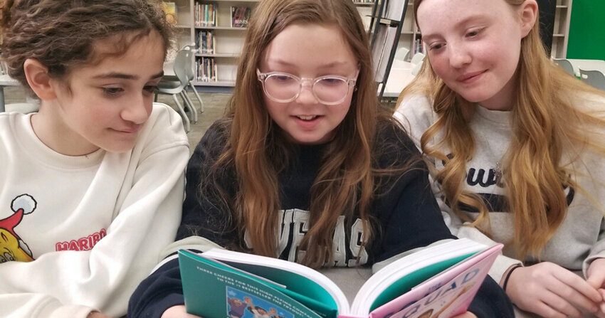 Austin Elementary School students Alexis Kitchen, Lydia Grzemski and Skylar Miller share a copy of The Squad by former WHS student Christina Soontornvat. The novel is now in all Weatherford elementary schools.