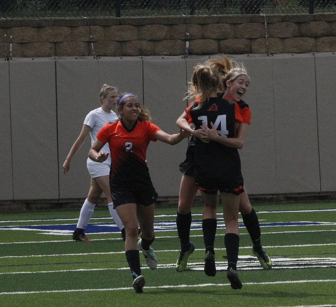 Aledo freshman defender Sydney Pierce (14) and sophomore midfielder Vanessa Rajan congratulate senior forward Peyton Laughley after her first-half goal during the Ladycats state semifinal match against Leander Rouse. Photo by Brad Keith