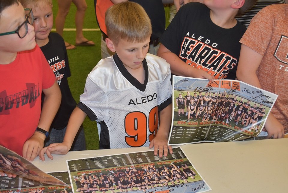Future Bearcat Wolfgang Maness (99) gets his team photo autographed by the Aledo Bearcats Thursday at Meet The Bearcats, Ladycats Night at The Indoor. Photo by Tony Eierdam