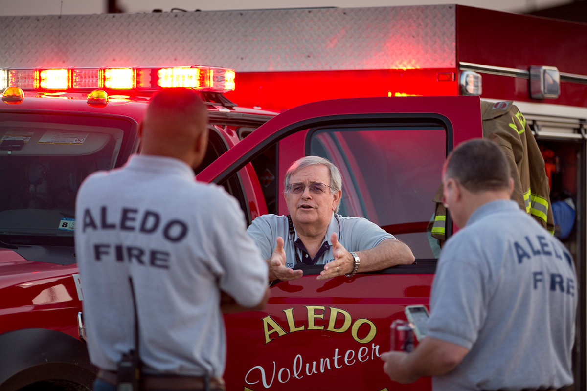 Jay Atwood, chaplain of the Aledo Volunteer Fire Department, talks to colleagues at a National Night Out event in 2012.