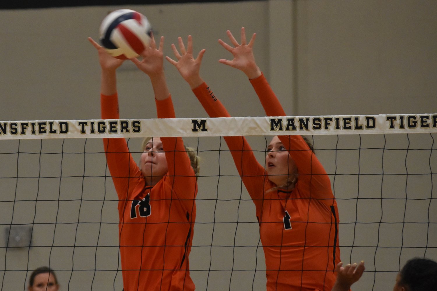 Payton Hilmer (18) and Maddie Frank (1) attempt to block the ball from getting over the net
