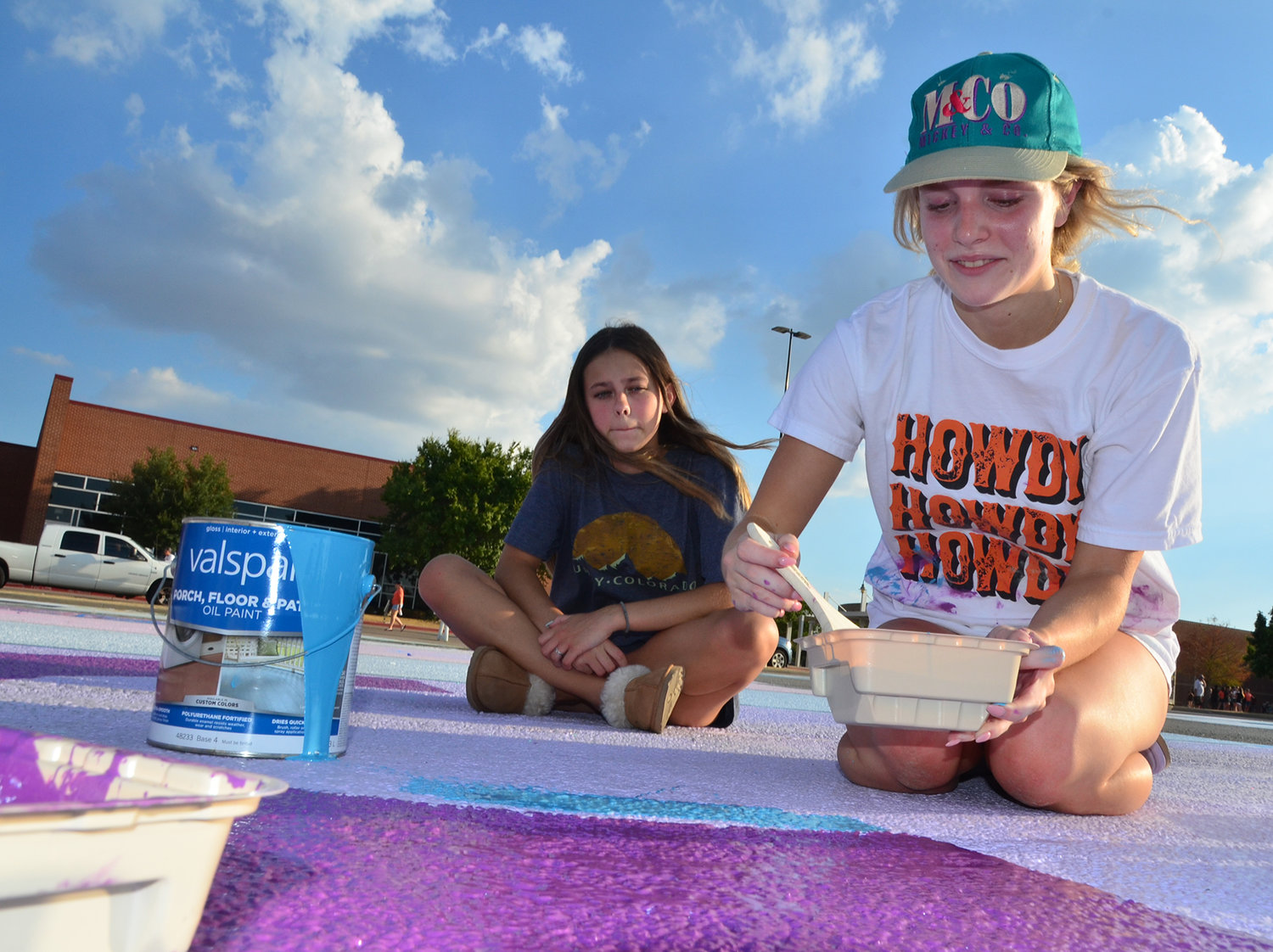 Seniors Ruthie Pulliam and Olivia Tontreras paint Olivia’s reserved parking space at Aledo High School. Dozens of seniors, many with parents, brought buckets, brushes and rollers to the parking lot on Friday, Aug. 12, to personalize each student’s special parking spot.