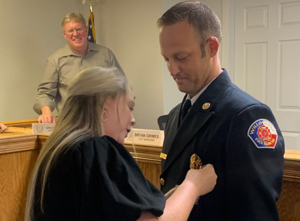 John Schneider was sworn in as Willow Park's new fire chief Tuesday. His wife, Stephanie, pins him while council member Greg Runnebaum looks on.