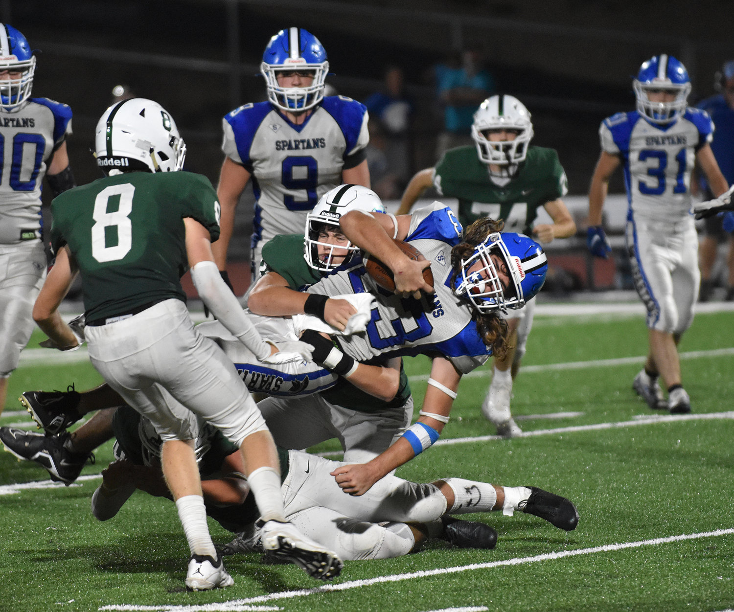 Spartans' quarterback Jordan Irby is upended by Trinity Christian's Kadin James (52) and  Riley McCracken (70). Also in on the play was Jake Anderson (8).