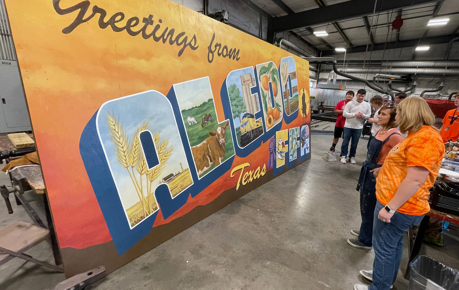Agricultural Science Instructor Krysti Kelley and artist Lisa Voight look over the mural before it is moved outside the ag building.