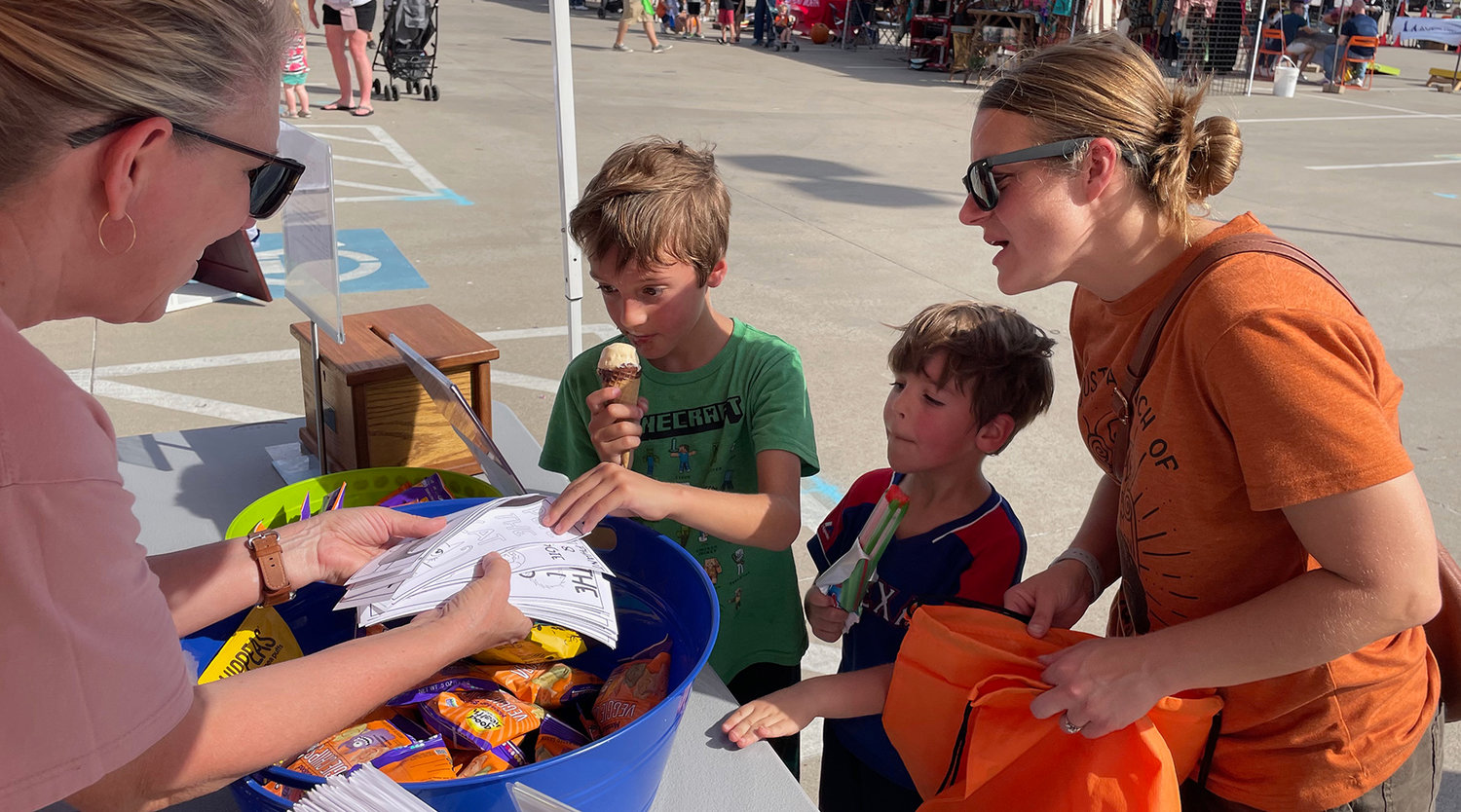 Caden and Damen Witt pick out bookmarks at the East Parker County Library booth with Megam Witt, their mom.