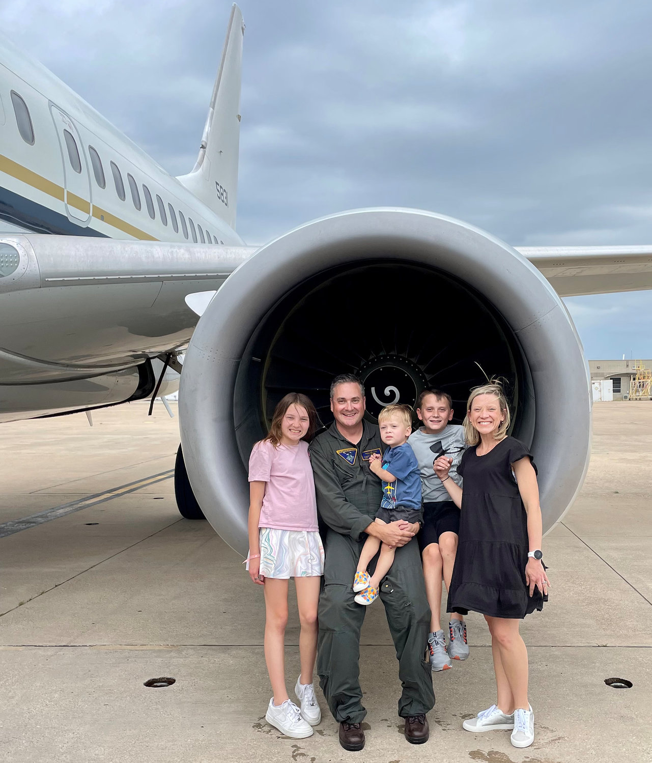 CDR Robert Gustavson is shown after his last flight with family members (from left) Adeline, Wyatt, Liam, and wife Holly.