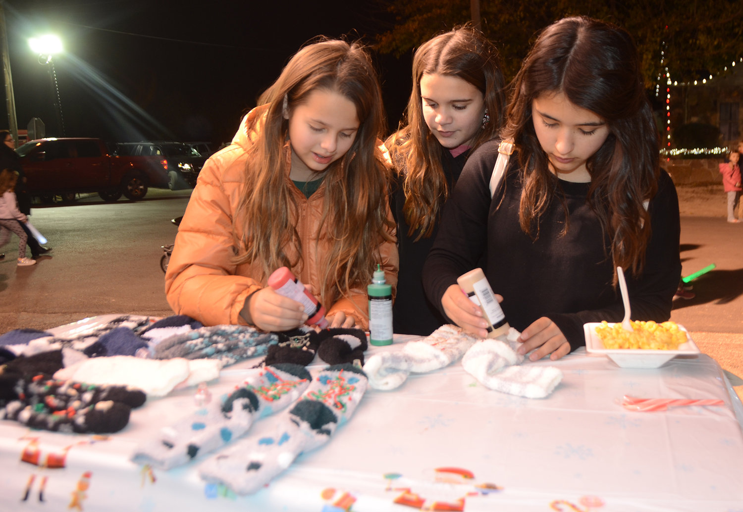 Friends Zoe Schuster, Dylan Formby, and Brynlee Hackfeld decorate socks that will be given to area nursing homes at the Aledo 4-H booth.