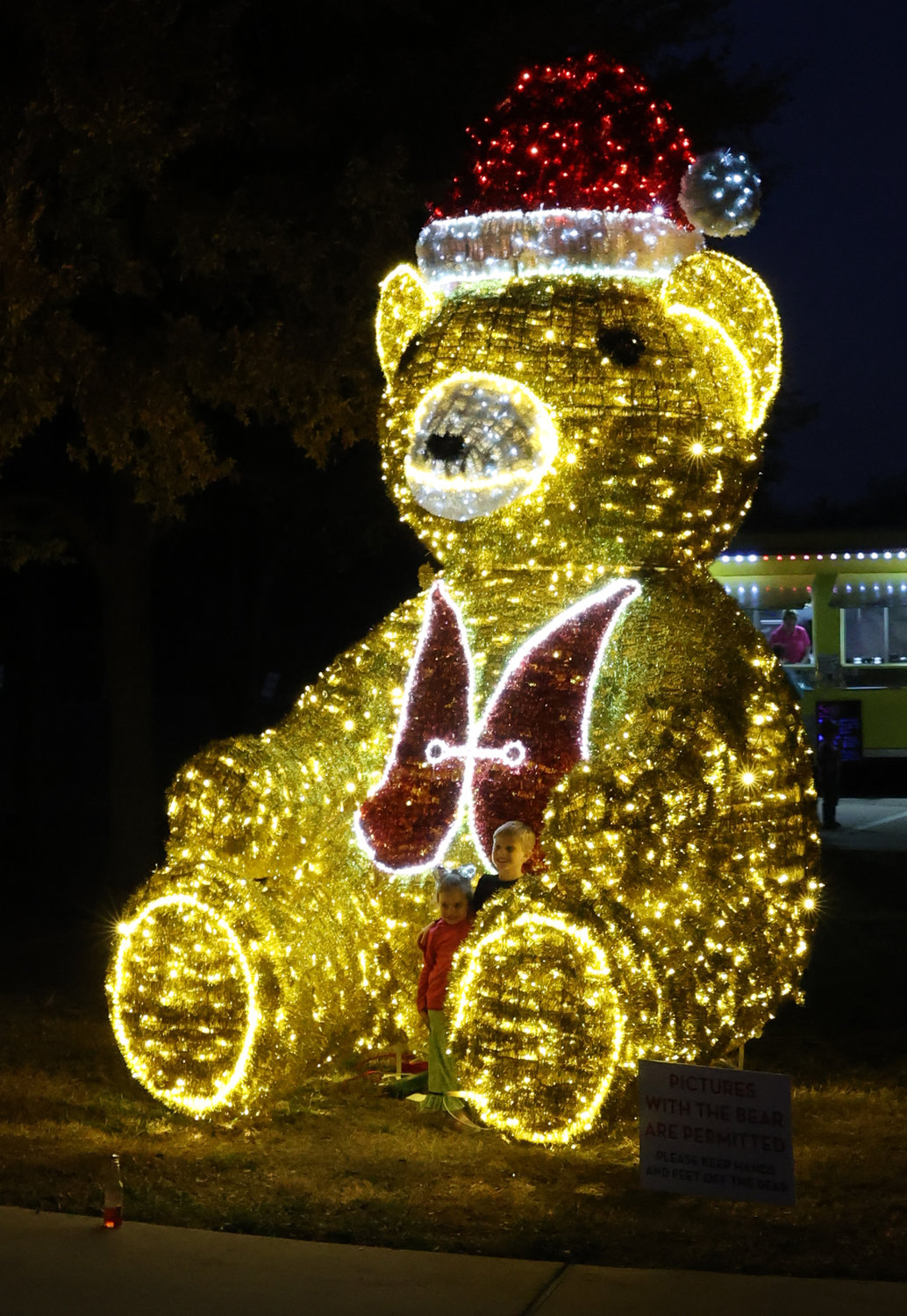 Children pose in the midst of the lighted bear.