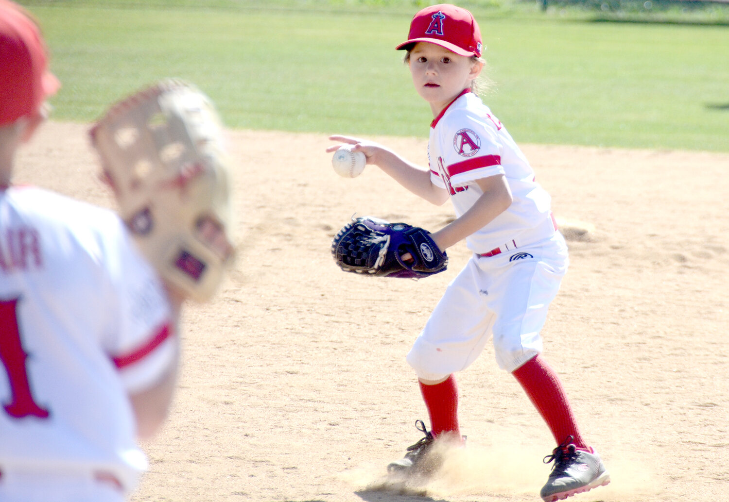 Second baseman Carter Blackburn of the Angels t-ball team throws to first.