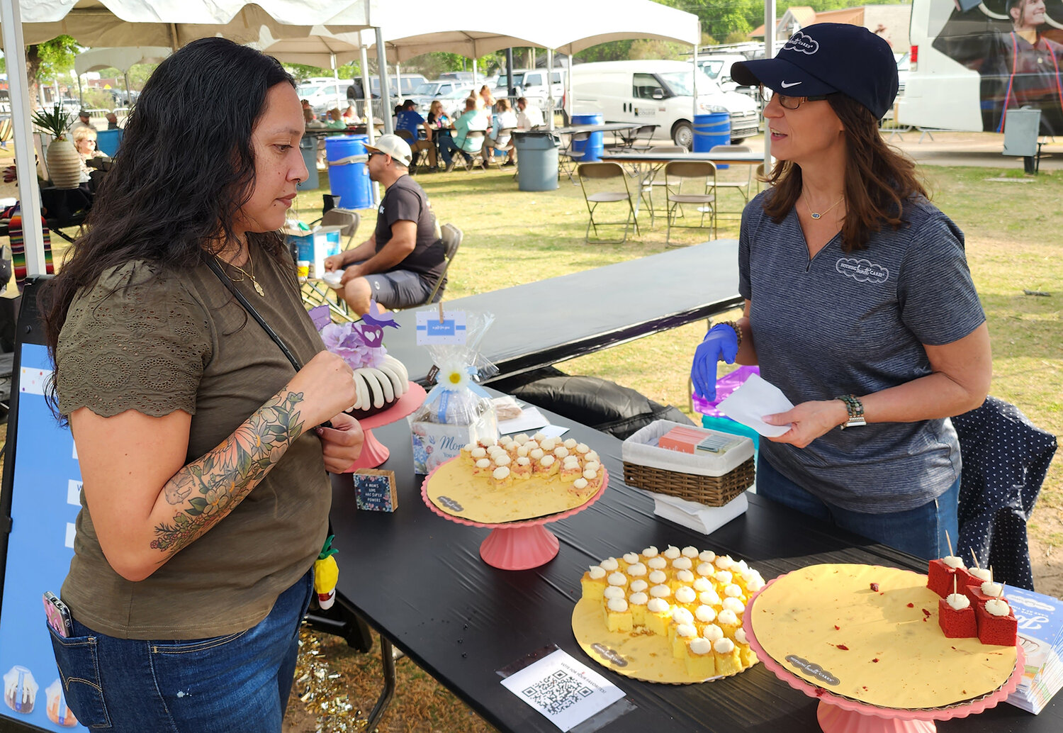 Cynthia Perez (l) takes a cake from Monica Valdez at the Nothing Bundt Cakes booth.