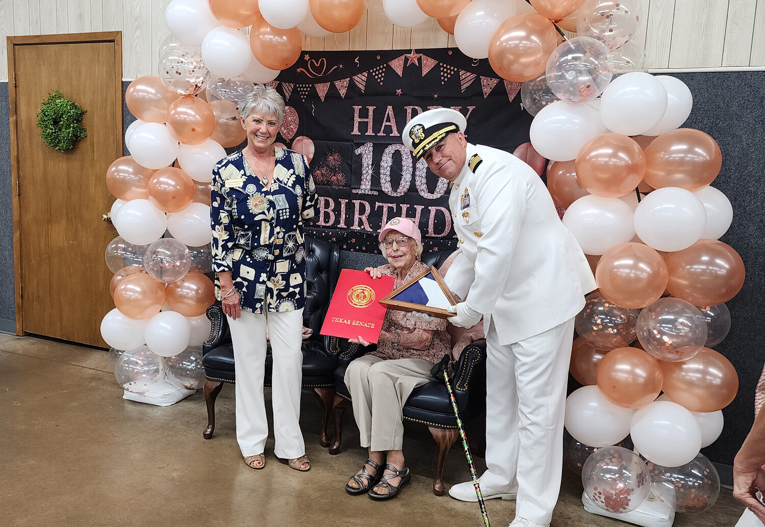 Judy Flanagin, with the assistance of Captain John Stuart US Navy, presents a flag on behalf of Senator Phil King's office to Jean Buford to honor her 100th birthday.