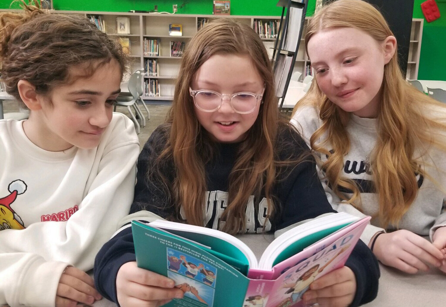 Austin Elementary School students Alexis Kitchen, Lydia Grzemski and Skylar Miller share a copy of The Squad by former WHS student Christina Soontornvat. The novel is now in all Weatherford elementary schools.