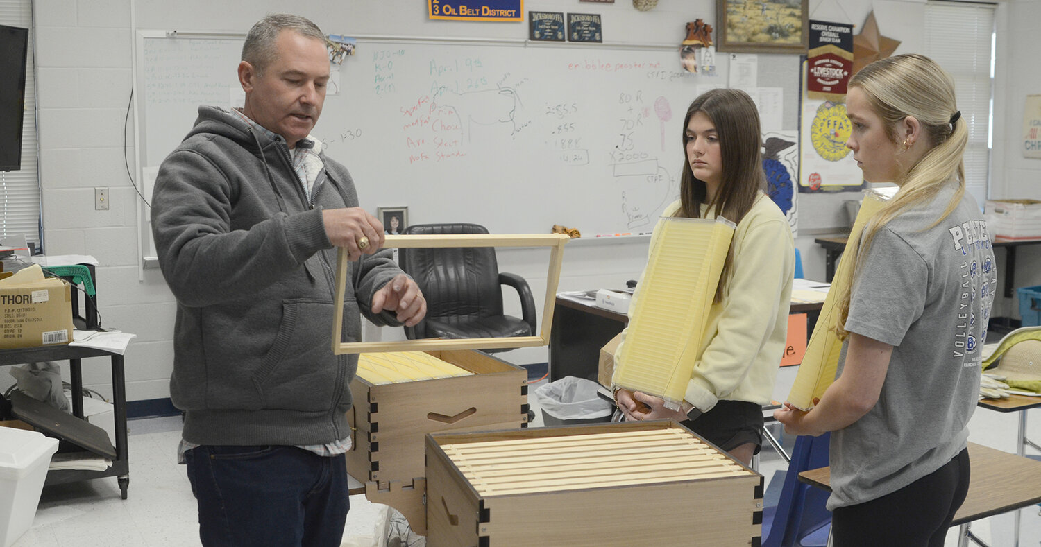 Peaster ag science instructor Eric Ribble shows cousins Hannah and Chloe Pilgrim a new bee hive the class will include with their bee apiary this spring.
