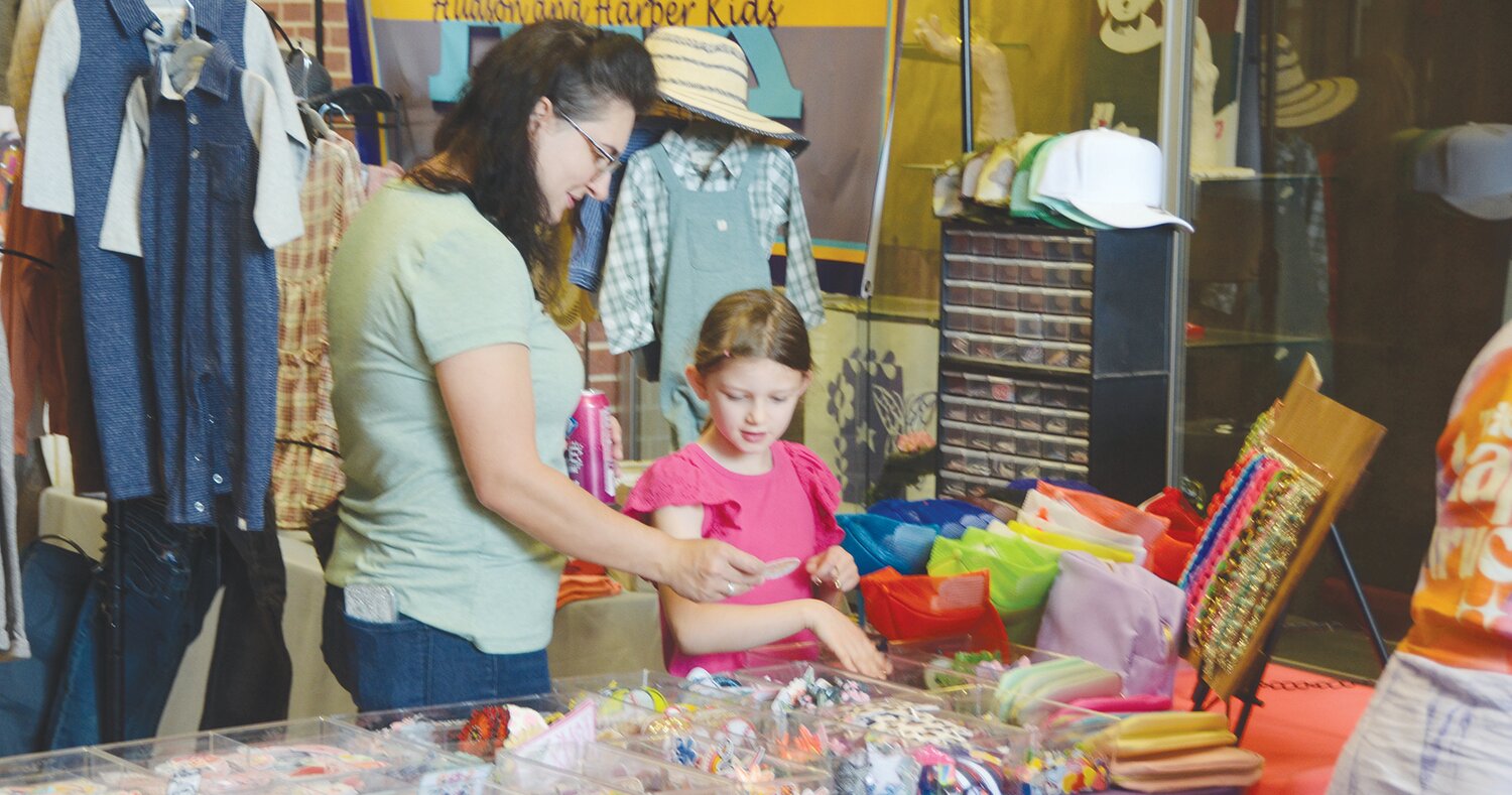 Nicole Stuart and daughter Sadie sort through apparel accessories at a booth.