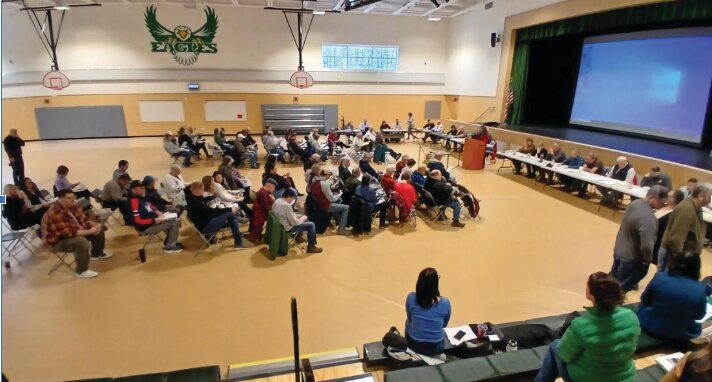 To safeguard the new parquet flooring in the gym, they installed large sheets of smooth fabric that were very easy to walk on. At the tables in front of the stage sat an array of 22 officials for the town, SAU, school board, and budget committee.