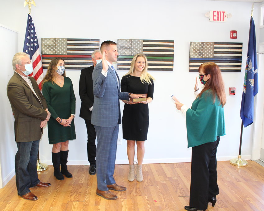 Assemblyman Colin Schmitt is administered the oath of Office by County Clerk Annie Rabbitt, Mrs. Nikki Schmitt holds the bible with family in the background.&nbsp;