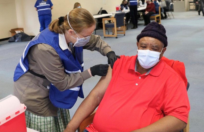 A volunteer nurse from the Bruderhof Community in Walden, administers a vaccination to Middletown&rsquo;s David Heath, 72