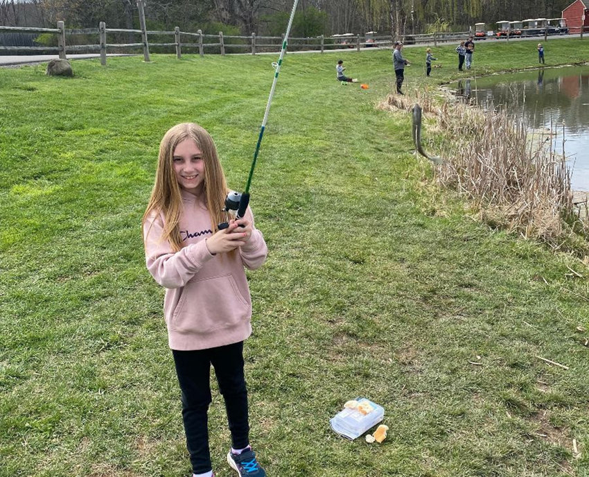A smiling library patron enjoys a fun day of fishing!&nbsp;Come check out a fishing pole from the Library of Things and have your own fun day or join the Youth Fishing Tournament on Saturday, May 14 from 8 a.m. - 12 noon at&nbsp;53 Reservoir Road in Highland.