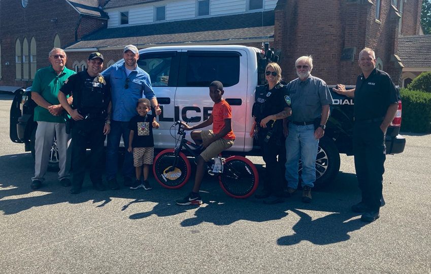 Members of the Town of Shawangunk Police Department, Supervisor John Valk and town police commissioners Brian Amthor and Robert Miller pose with a child with his donated bike from the town. The donation is part of the National Night Out program put on by the Shawangunk Police Benevolent Association (PBA) Aug. 4 at Garrison Park in Wallkill.