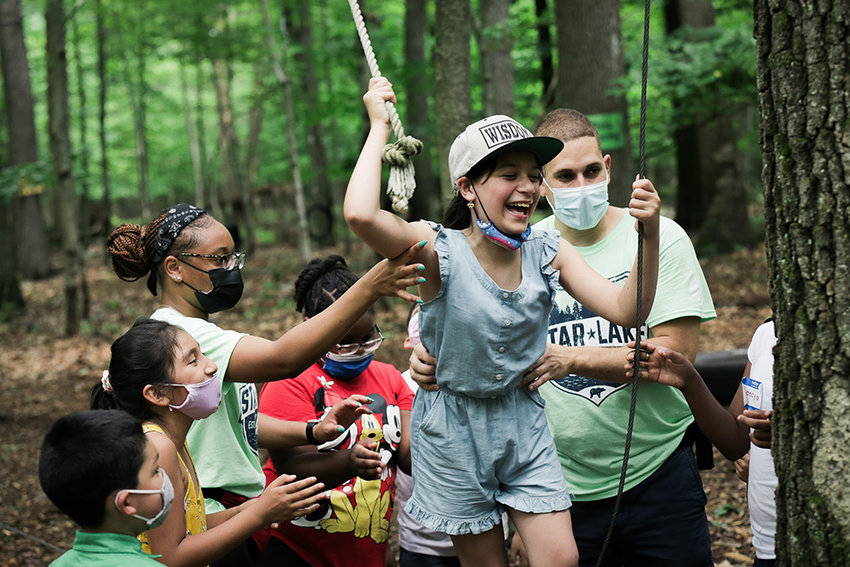 Several campers and counselors enjoy a fun time at a ropes/obstacle course.