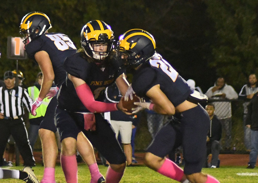Pine Bush quarterback Danny DeGroodt hands the football off to Mike DeSena as Mason Miranowicz blocks during Friday&rsquo;s Class AA football game at Pine Bush High School.