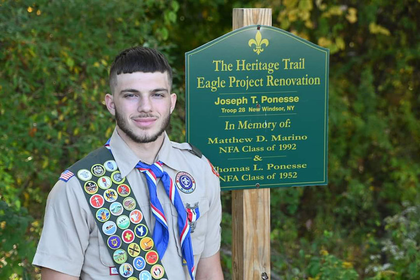 Eagle Scout Joe Ponesse with Heritage Trail sign made by volunteers.