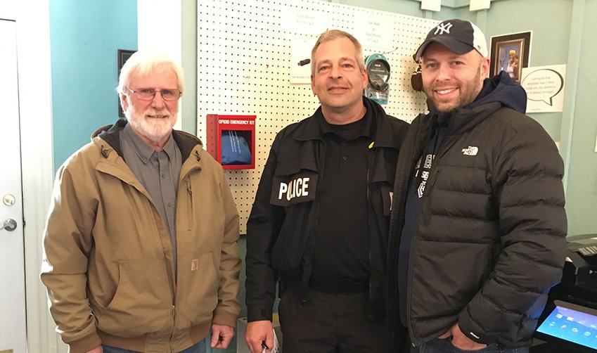 Town of Shawangunk Councilmen Robert Miller and Brian Amthor flank Police Chief Gerald Marlatt in front of an opioid emergency kit at the Town Hall.