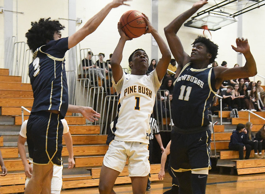 Pine Bush's Manny Hannon tries to shoot over Newburgh's Aidan Brown (3) and Deondre Johnson (11) during Wednesday's OCIAA crossover boys' basketball game at Pine Bush High School.