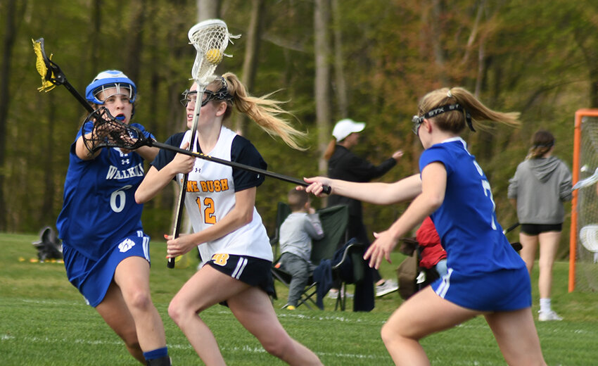 Pine Bush&rsquo;s Samantha Budney runs through the defense of Wallkill&rsquo;s Paige Badner and Emma DiLemme during Thursday&rsquo;s non-league girls&rsquo; lacrosse game at Pine Bush Elementary School.