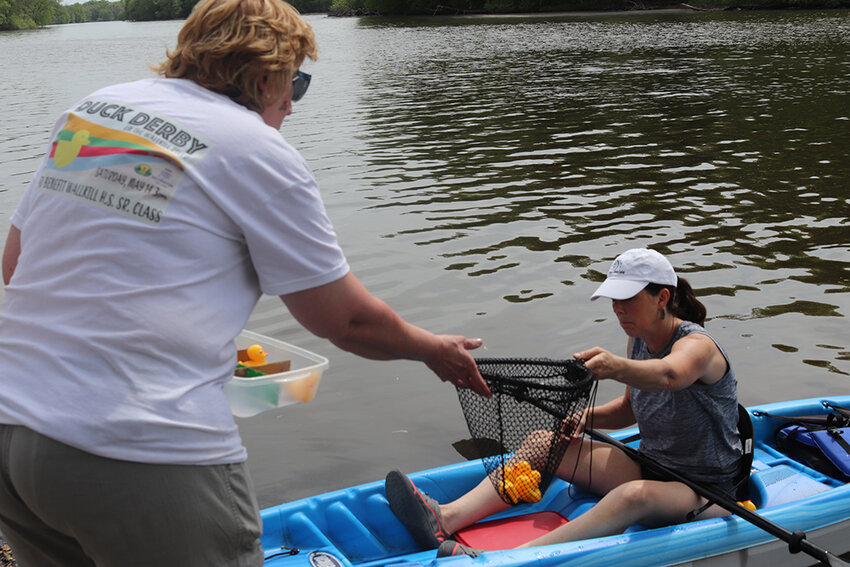 Volunteer kayaker hands event co-chair Donna Barczak the winning ducks.