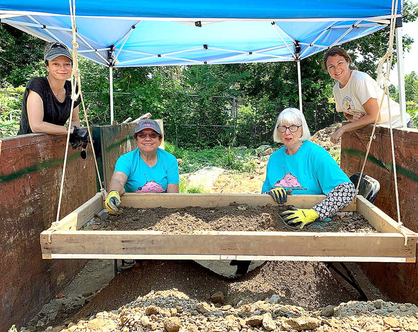 Volunteers place dirt into sifters and search for artifacts within.