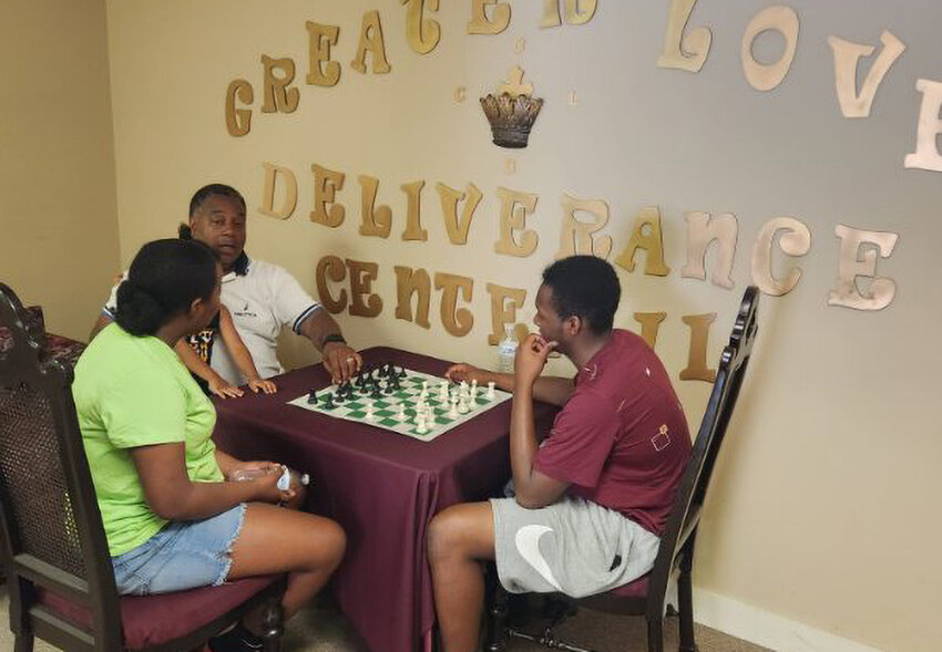 Bishop Troy Johnson teaches chess to a young brother-sister duo.