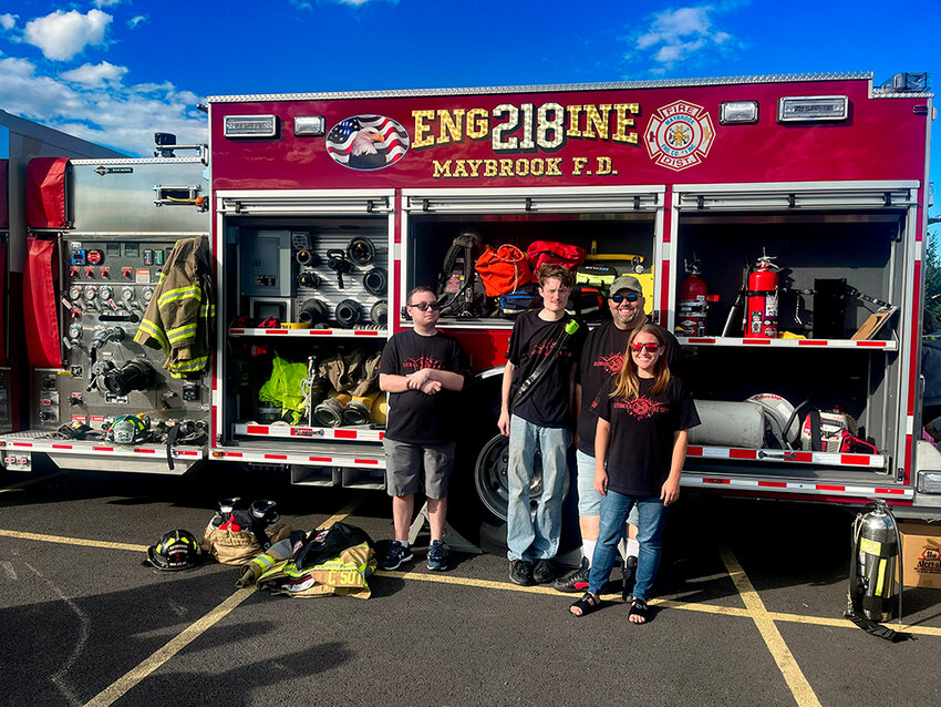 Members and volunteers of the Maybrook Fire Department gathered by their fire truck. They gave kids fire hats and let them explore the fire truck.