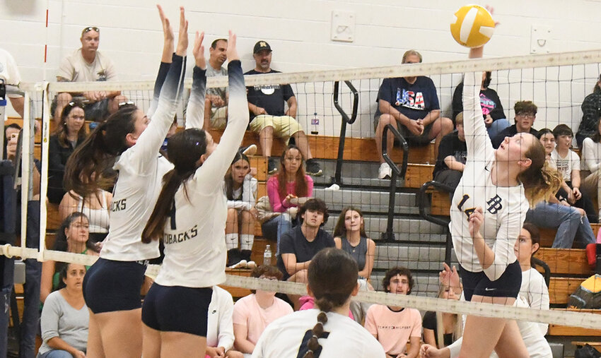 Pine Bush's Ellie Hoppe hits the ball over the net as Newburgh's Makayla Rafferty and Sofia Mucci go up to block and Megan Evans looks on during Friday's OCIAA Division I volleyball match at Newburgh Free Academy's Main Campus.